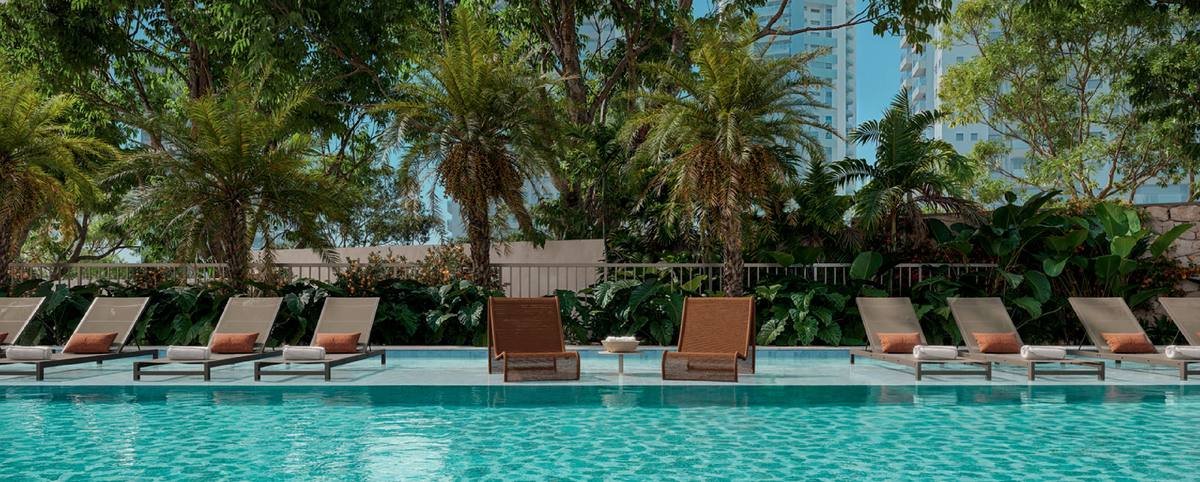 Deck da piscina do Kronos by Tegra com espreguiçadeiras e vegetação