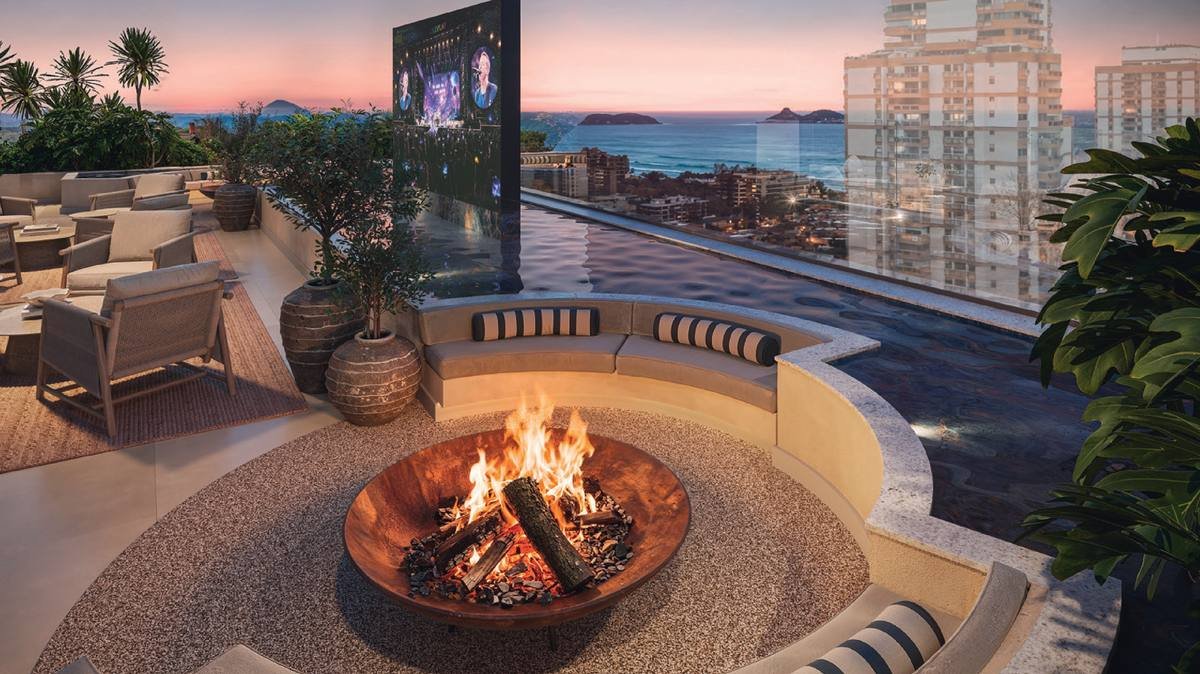 Lounge do rooftop do Kronos by Tegra com fogueira e vista para o pôr do sol na Barra