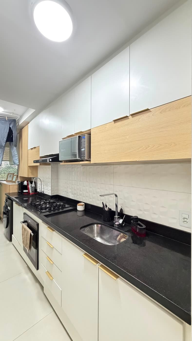 Bancada de granito com cooktop e forno embutido na cozinha do apartamento