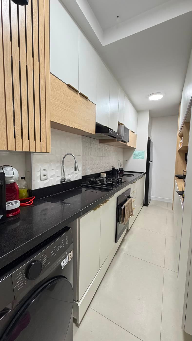 Cozinha planejada com bancada de granito preto e armários até o teto no Maayan