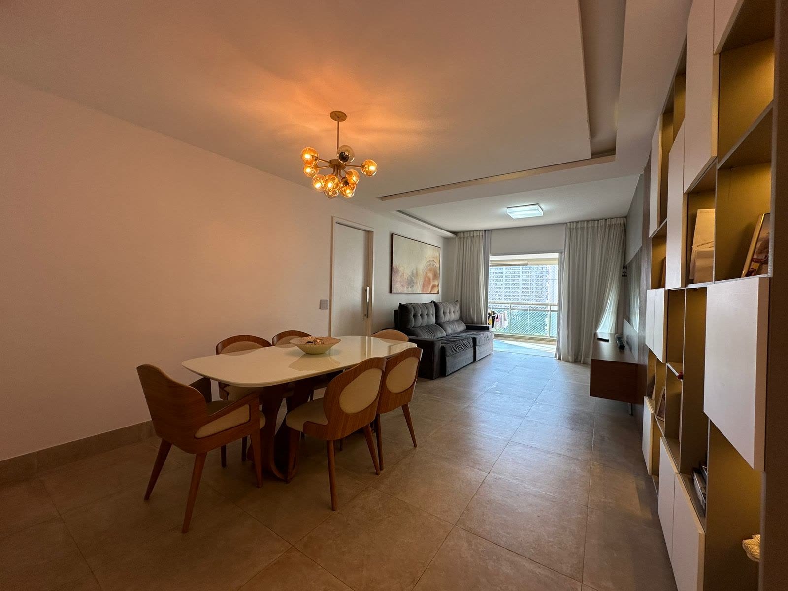 Sala com acesso à varanda com cortina de vidro no apartamento do Reserva Jardim