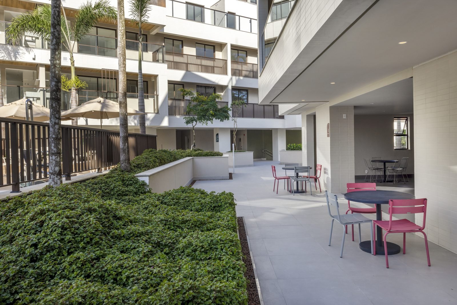 Área de convívio externa do All Jardim Oceânico, com mesas e cadeiras sob a laje