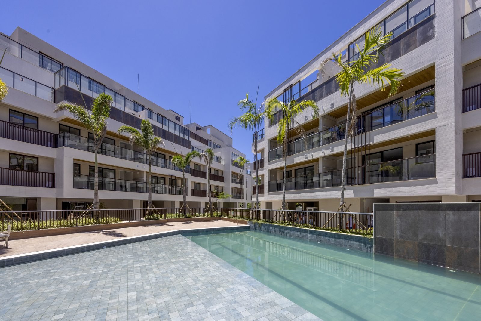 Piscina do All Jardim Oceânico entre os edifícios, com palmeiras e deck