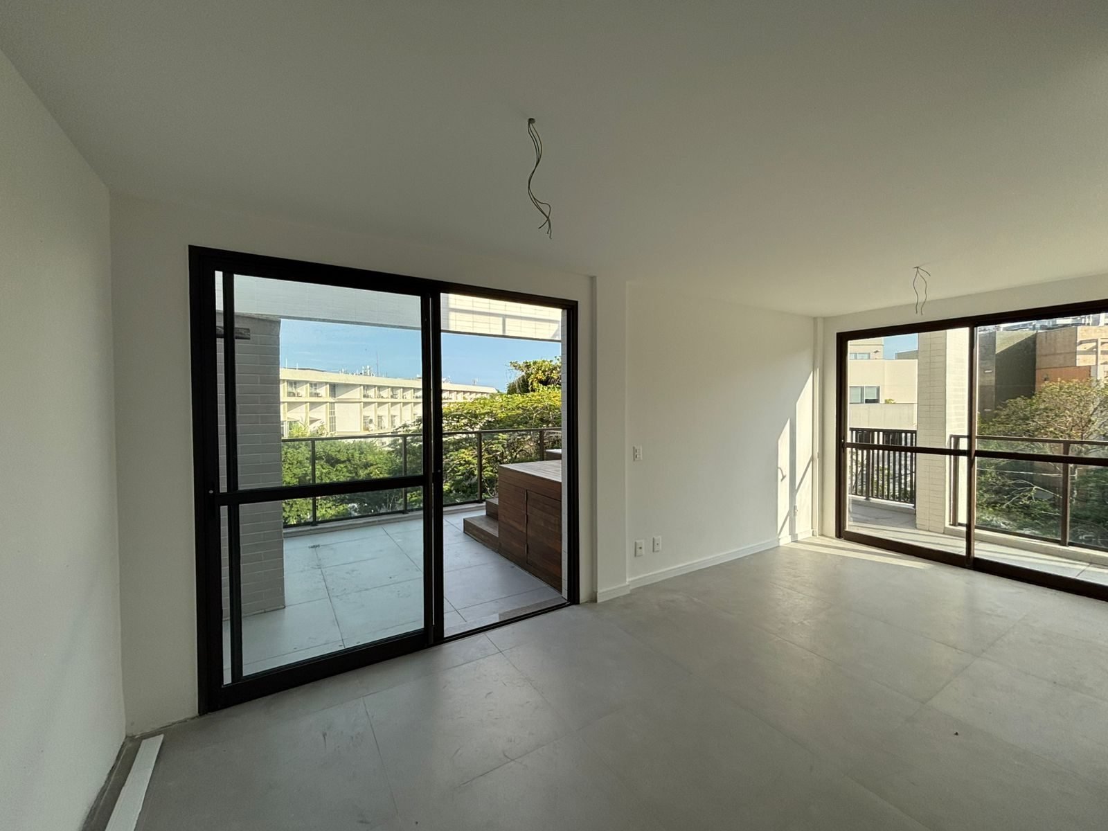 Sala da unidade 309 do All Jardim Oceânico, com pé-direito duplo e porta de vidro para a varanda