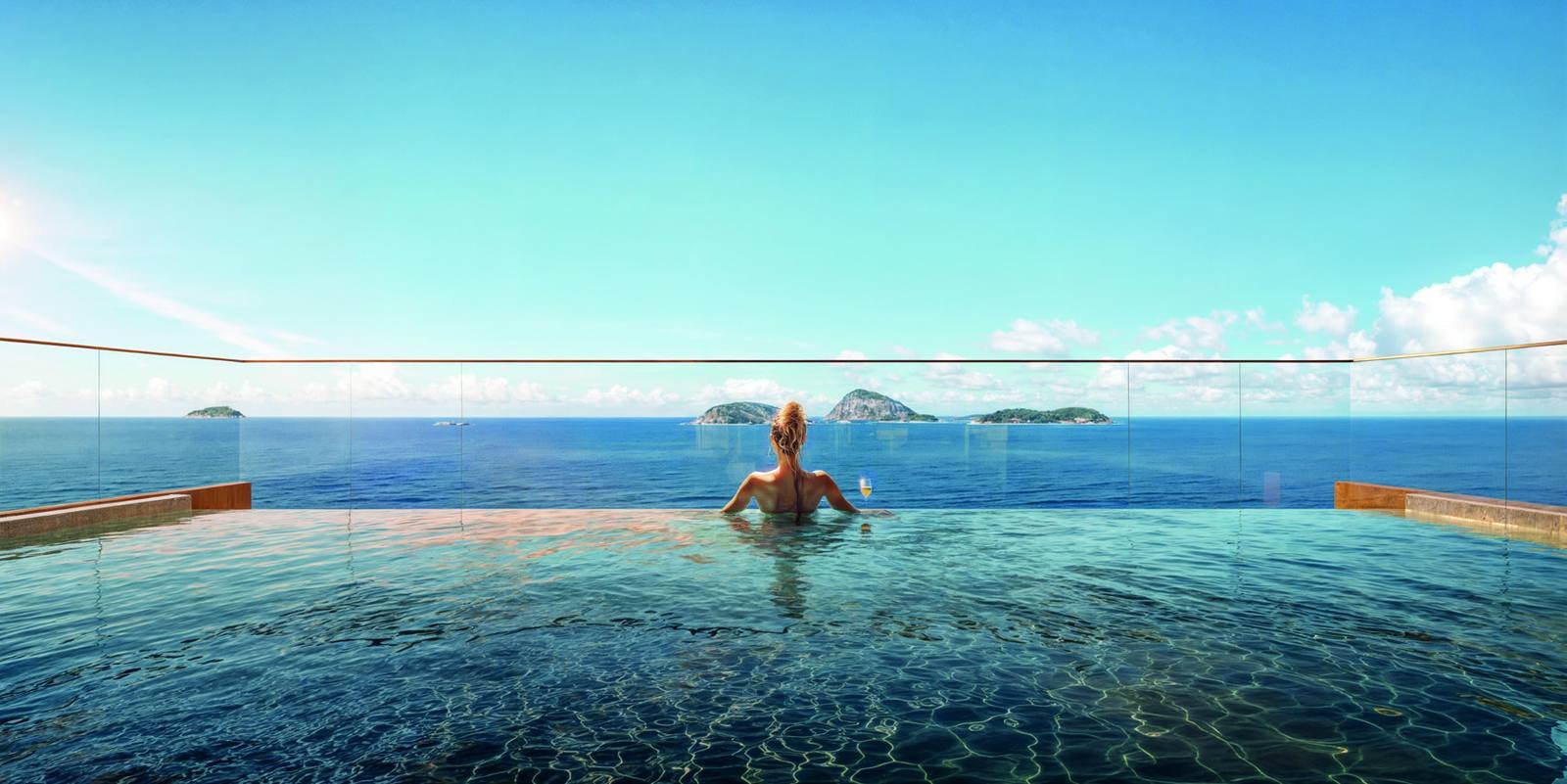 Piscina de borda infinita do rooftop do Bronze Ipanema Studios, com pessoa na água e o mar ao fundo