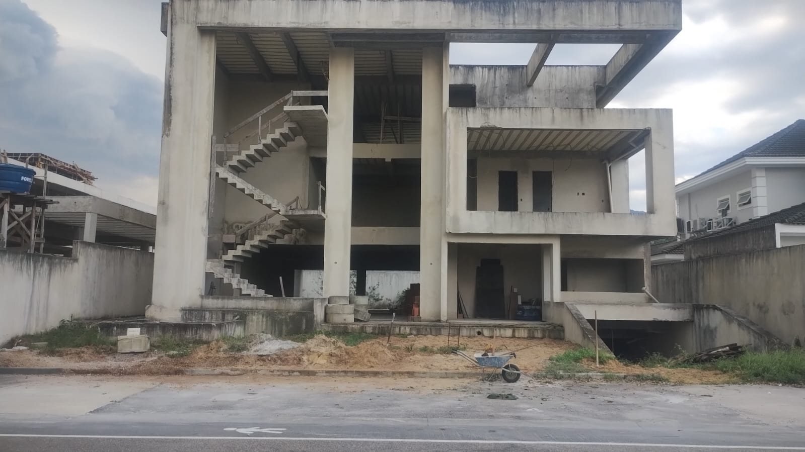 Obra da casa de 4 suítes na Barra da Tijuca em setembro de 2026, com a estrutura de concreto concluída, escadas e rampa do subsolo