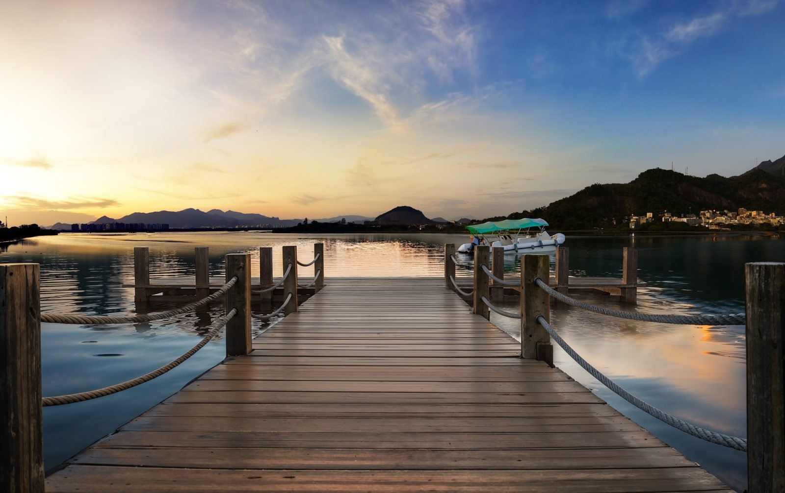 Deck de acesso à balsa na lagoa, com praça de chegada arborizada