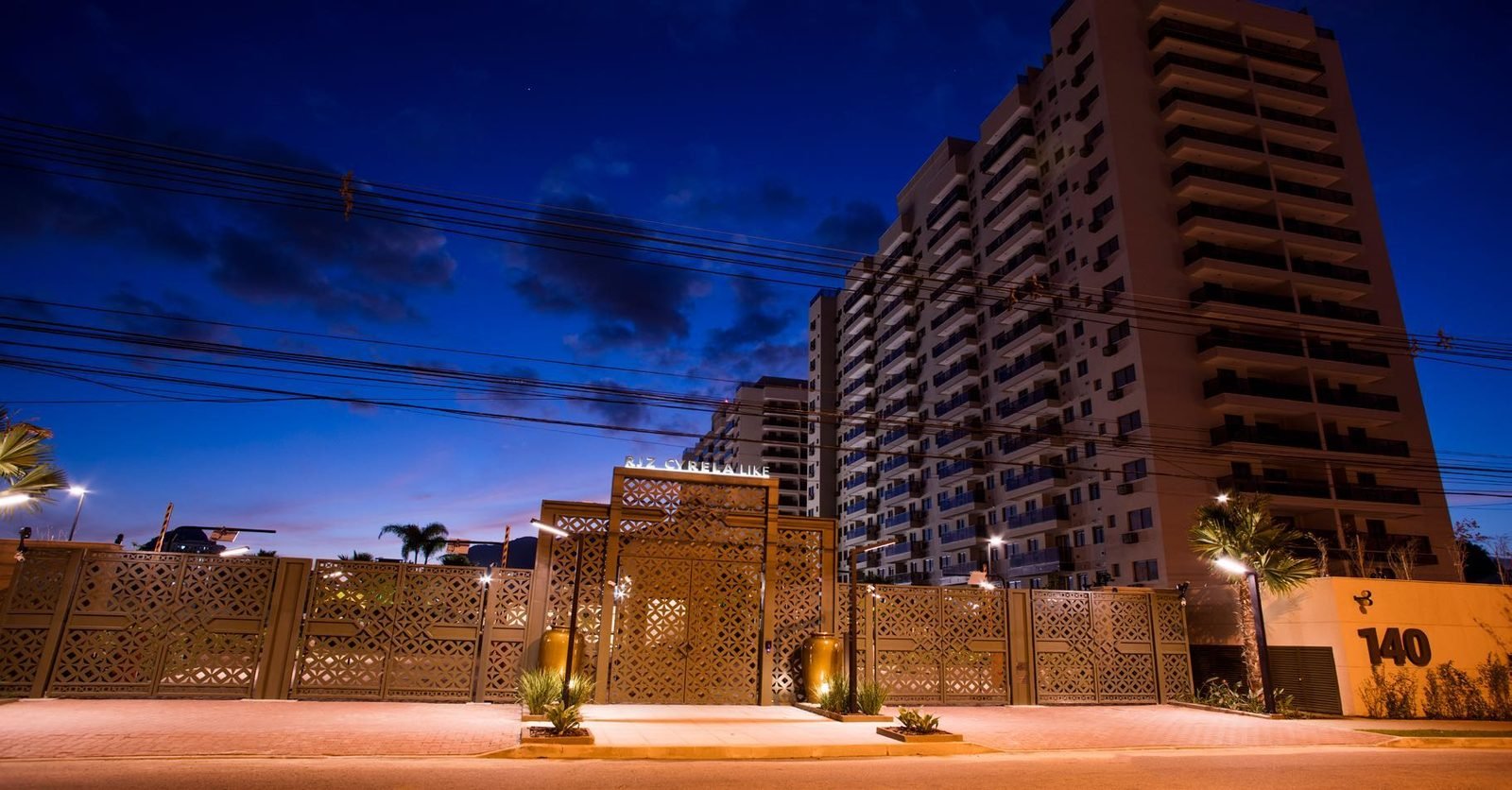 Fachada do Like Residencial Club à noite, com o acesso de pedestres e o número 140