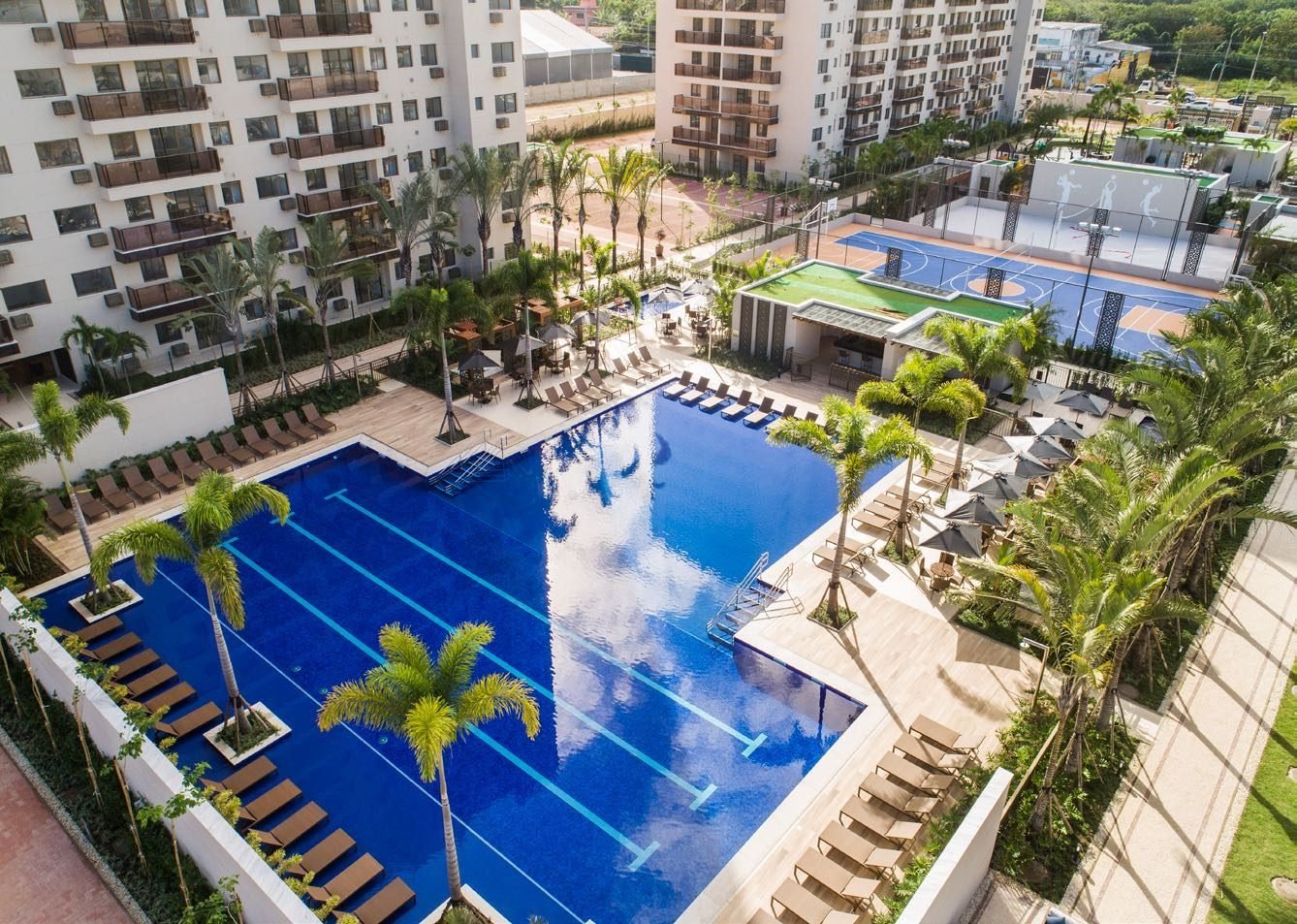 Vista aérea das piscinas do Like Residencial Club, com piscina de raia, deck e os edifícios ao redor
