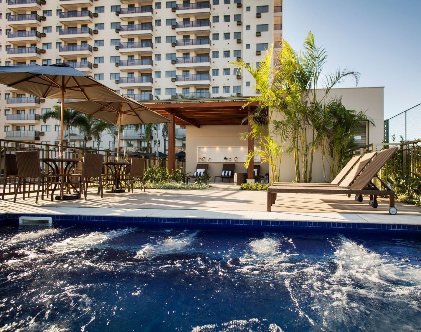 Spa com hidromassagem ao ar livre do Like Residencial Club, com espreguiçadeiras e ombrelones