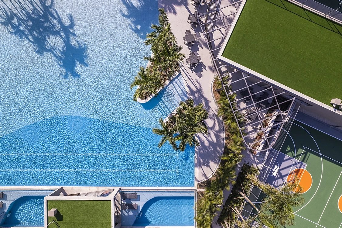 Vista aérea das piscinas e das quadras poliesportiva e de tênis do Orygem