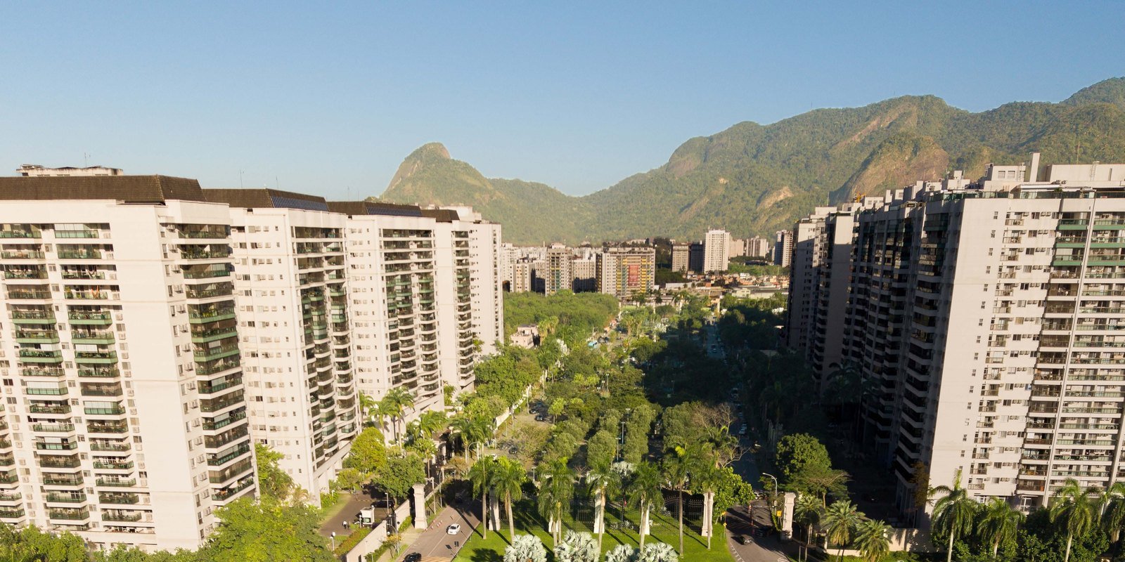 Vista aérea do bairro Cidade Jardim, na Barra Olímpica, com o boulevard arborizado entre os edifícios e o maciço da Pedra Branca ao fundo